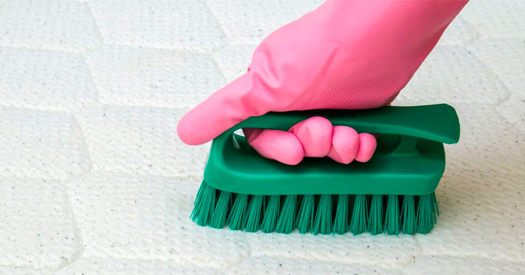Cleaning a memory foam mattress using a brush